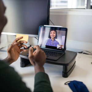 Businessman sitting at his office desk and talking with female colleague on video call. Business people video conferencing on laptop at office.