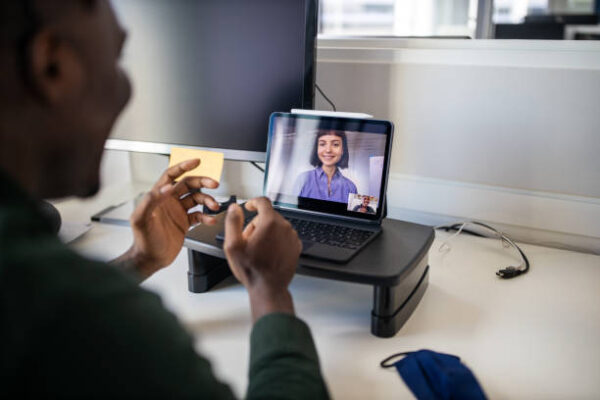 Businessman sitting at his office desk and talking with female colleague on video call. Business people video conferencing on laptop at office.